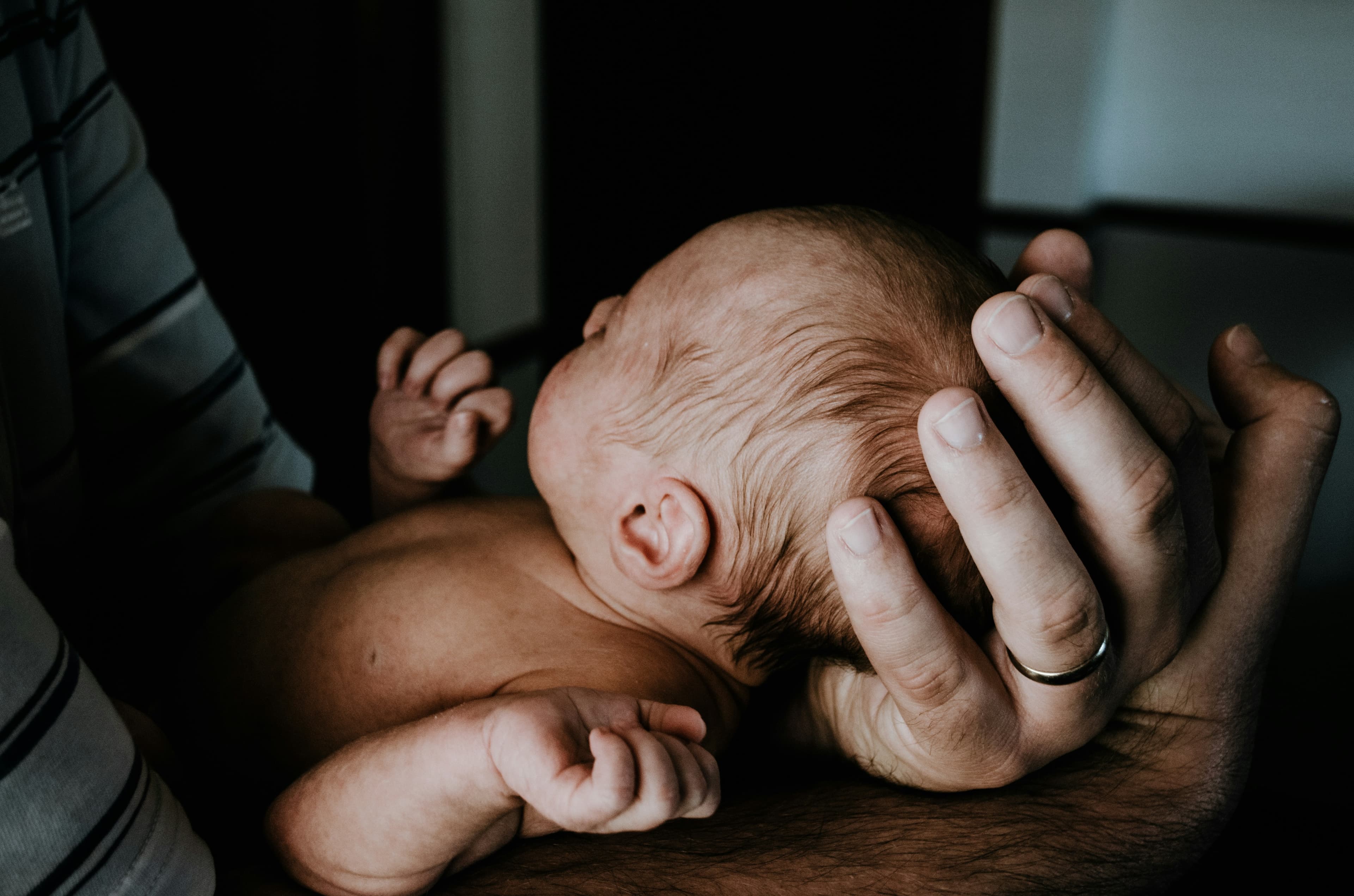 Newborn baby cradled gently in a parent's hands